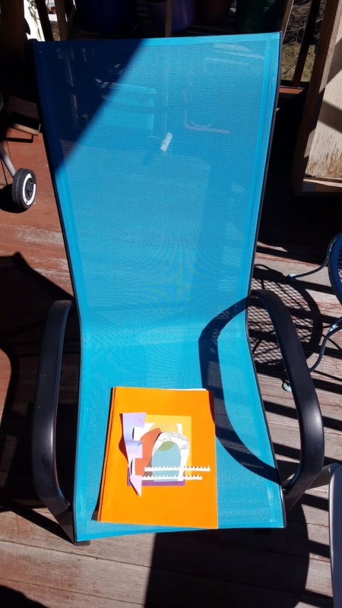 A decorated fabric quilt square sitting on a lawn chair outside on a porch.